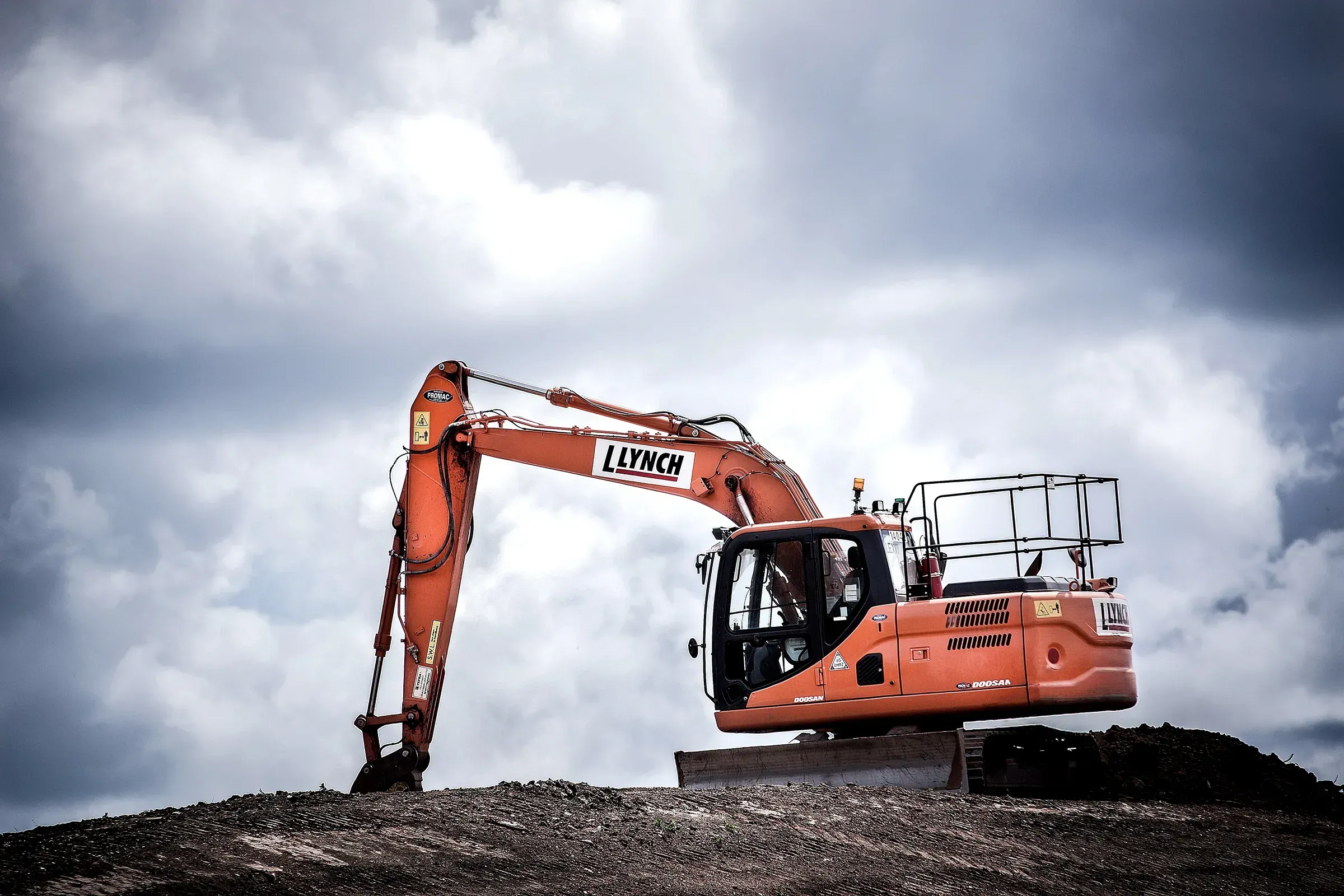 Excavator on a construction site under a storm sky